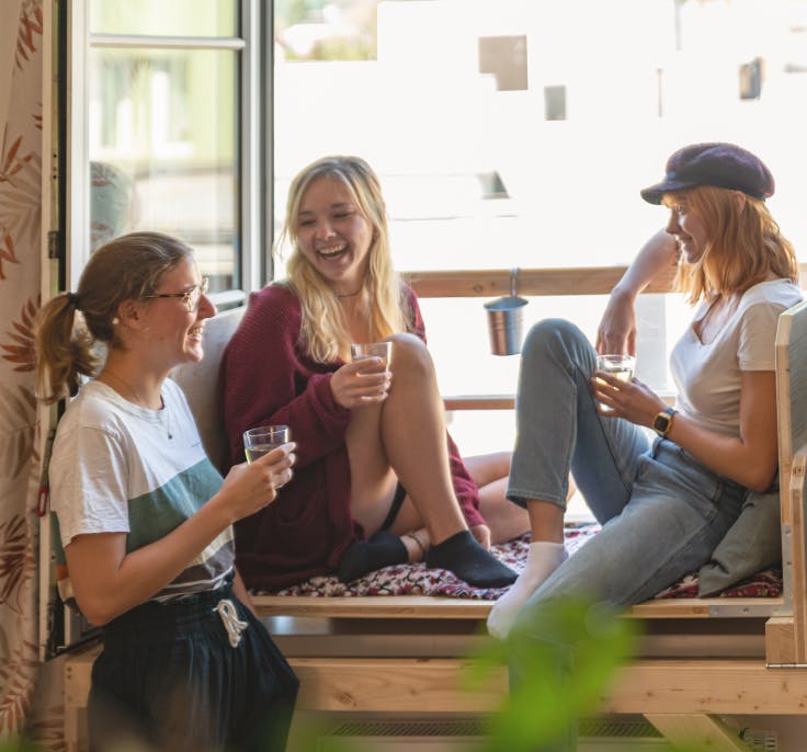 Drei Frauen sitzen am Balcosy und lachen